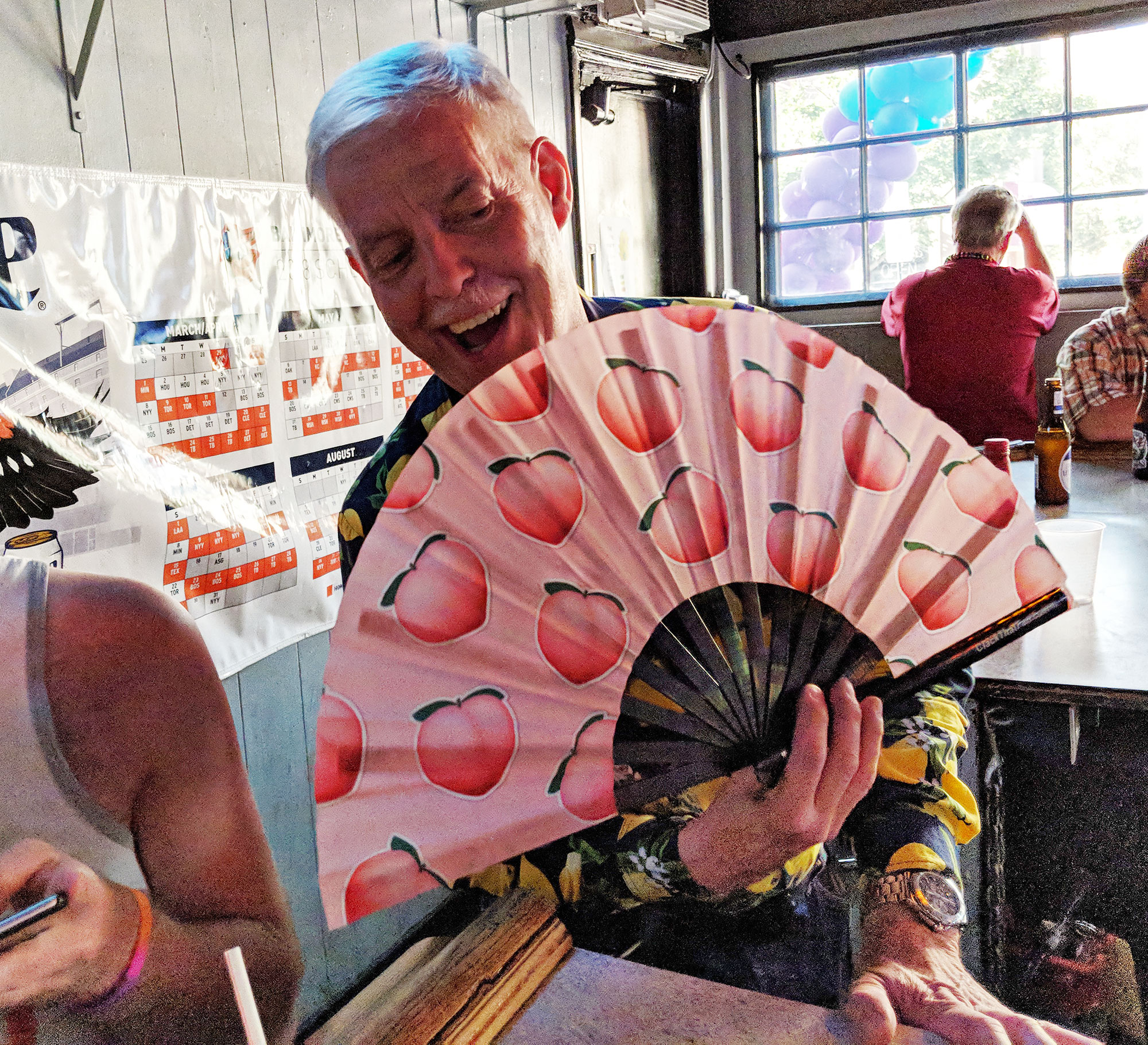 A man clacking the fan at "The Drinkery" bar in Baltimore.