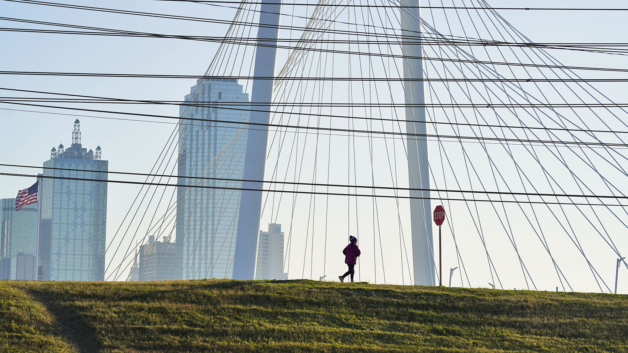 A woman jogs along the Trinity River trail in Dallas, with downtown in the background.